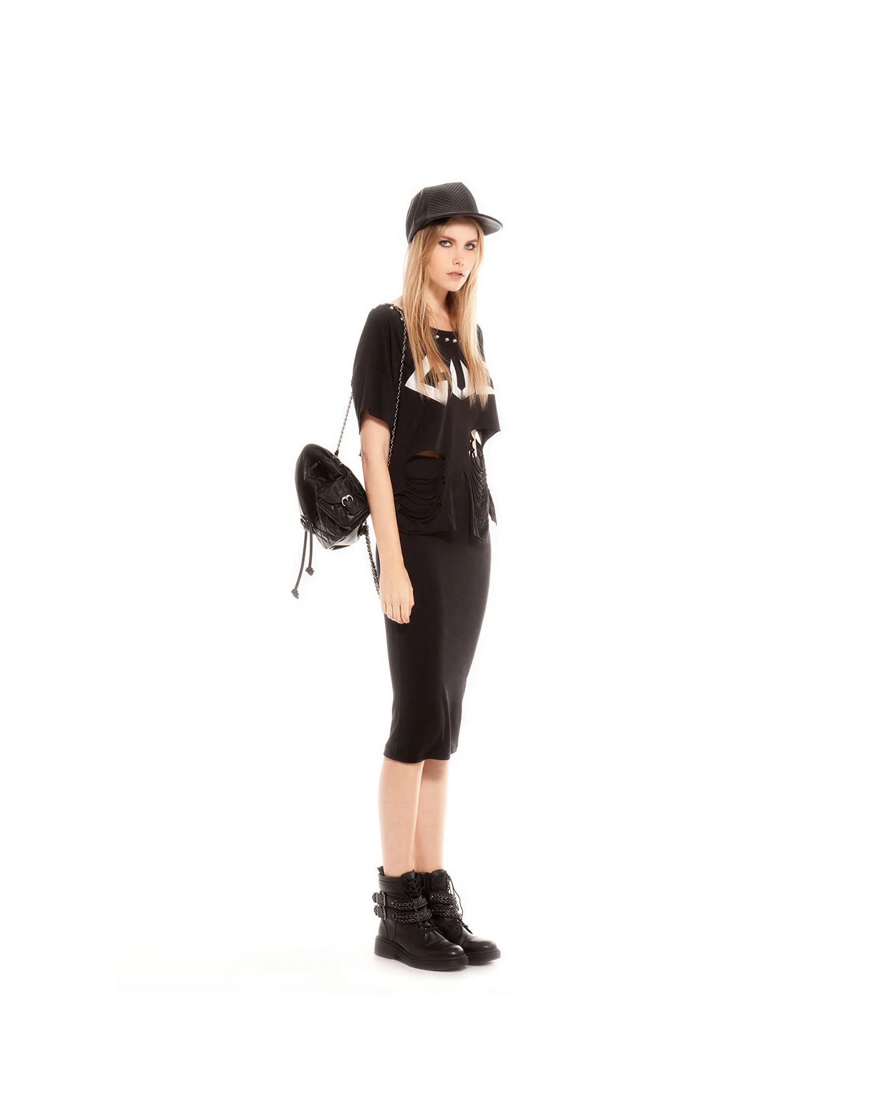 Full black studio look: printed tee, pencil skirt, cap, chained backpack and buckle boots